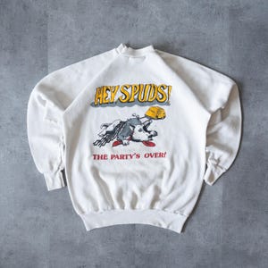 Könnte beinhalten: Weißer Pullover mit einem Cartoon-Hund, der einen Hut trägt und den Text "Hey Spuds! The Party's Over!"