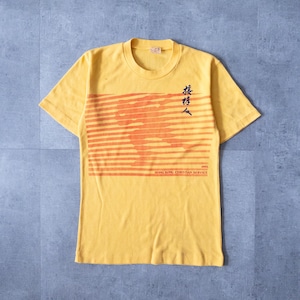Könnte beinhalten: Senfgelbes T-Shirt mit einem horizontalen orangefarbenen Grafikdesign. Das T-Shirt hat Text in englischer und chinesischer Schrift. Der Text enthält "Hong Kong Christian Service" und das Jahr "1983".