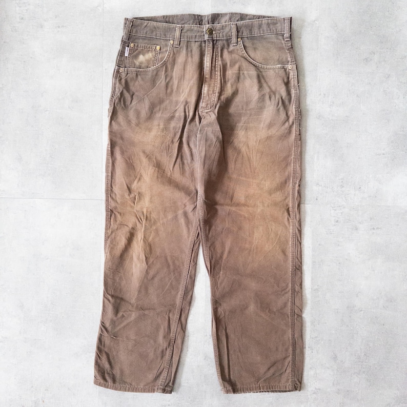 Puede incluir: Pantalones de pana marrones con un dise&ntilde;o cl&aacute;sico de cinco bolsillos. Los pantalones tienen un aspecto descolorido y un corte recto. La tela parece ser una pana de peso medio, adecuada para ropa informal. Los pantalones est&aacute;n colocados sobre una superficie clara.