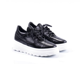 May include: Pair of black leather sneakers with white platform soles and lace-up closure.