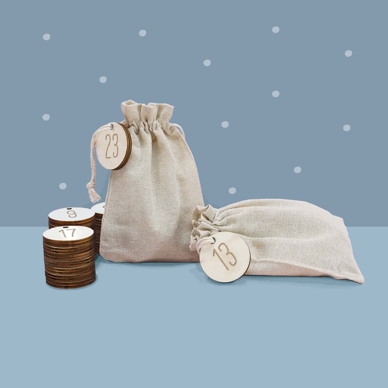 May include: A set of wooden Christmas advent calendar numbers in a burlap sack. The numbers are 9, 13, 17, and 23. The sack is beige and has a drawstring closure.