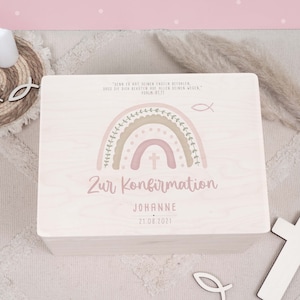 Peut inclure: Une boîte en bois avec un motif arc-en-ciel rose et vert. La boîte porte l'inscription "Zur Konfirmation JOHANNE 21.08.2021" sur le devant. La boîte est un cadeau pour une confirmation.
