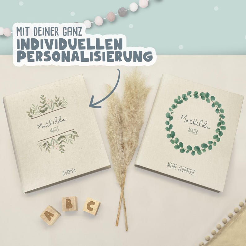 May include: Two beige fabric-covered folders with personalized text and green botanical illustrations. The left folder features the name Mathilda Maier and the word Zeugnisse. The right folder shows a green leaf wreath, the name Mathilda Maier, and the text Meine Zeugnisse. A blue arrow points to the left folder.