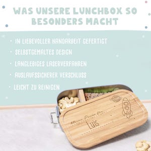 May include: A light blue metal lunchbox with a bamboo lid. The lid has a rocket ship and planet design with the text "kleine Pause f&uuml;r Luis".