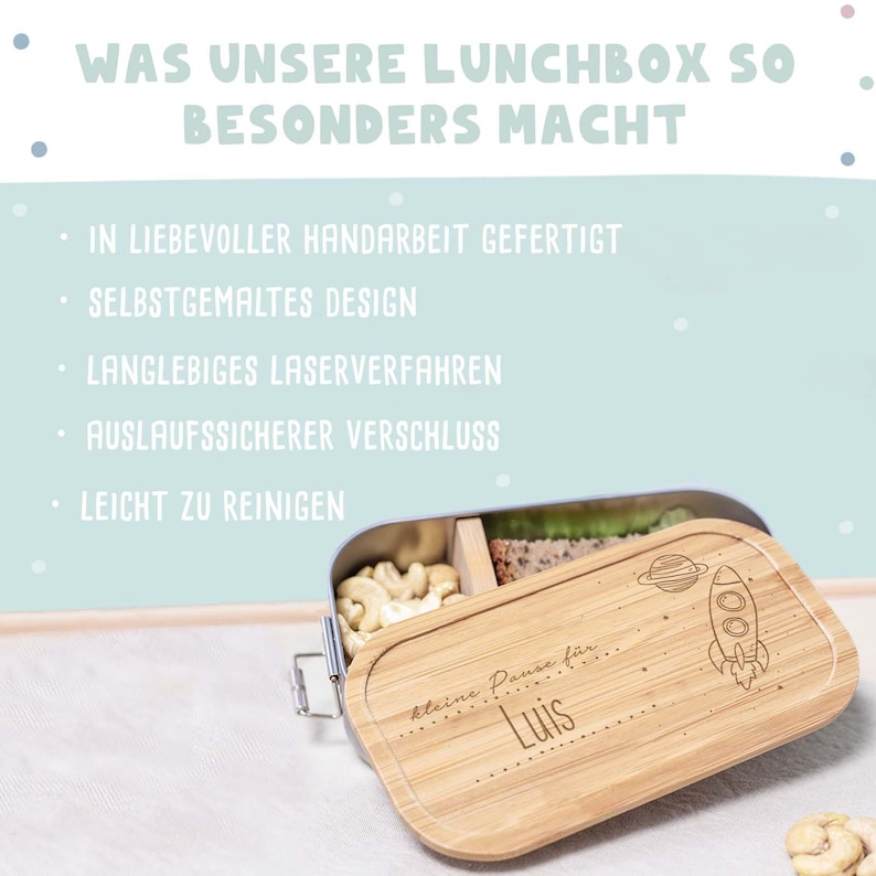 May include: A light blue metal lunchbox with a bamboo lid. The lid has a rocket ship and planet design with the text "kleine Pause f&uuml;r Luis".