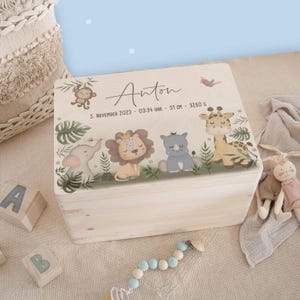 Può includere: Una scatola di legno per ricordi con una finitura in legno chiaro e un'illustrazione colorata di animali della giungla. La scatola è decorata con il nome Anton, la data 5 novembre 2023 e l'ora 03:34, insieme alle misure 51 cm e 3260 g.