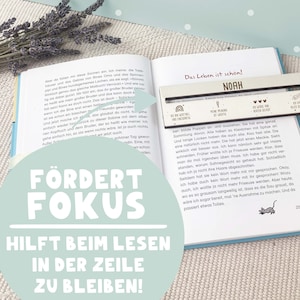 May include: A close-up of a book with the title "Das Leben ist sch&ouml;n!" and the name "Noah" on the cover. The book is open to a page with text about a child's experience with a friend and a doll. The book is designed to help children learn to focus while reading.