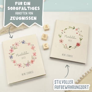 May include: Two off-white binders with a floral wreath illustration, the name Mathilda Maier, and the text Meine Zeugnisse. Three wooden blocks with the letters A, B, and C are placed between the binders. Text overlays read F&uuml;r ein sorgf&auml;ltiges Abheften von Zeugnissen and Stilvoller Aufbewahrungsort.