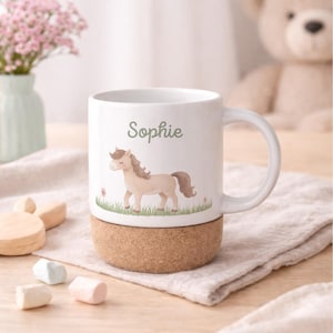May include: White ceramic mug with a cork base, featuring a watercolor illustration of a tan pony and the name "Sophie" in green. The mug has a curved handle and is set on a light-colored surface.