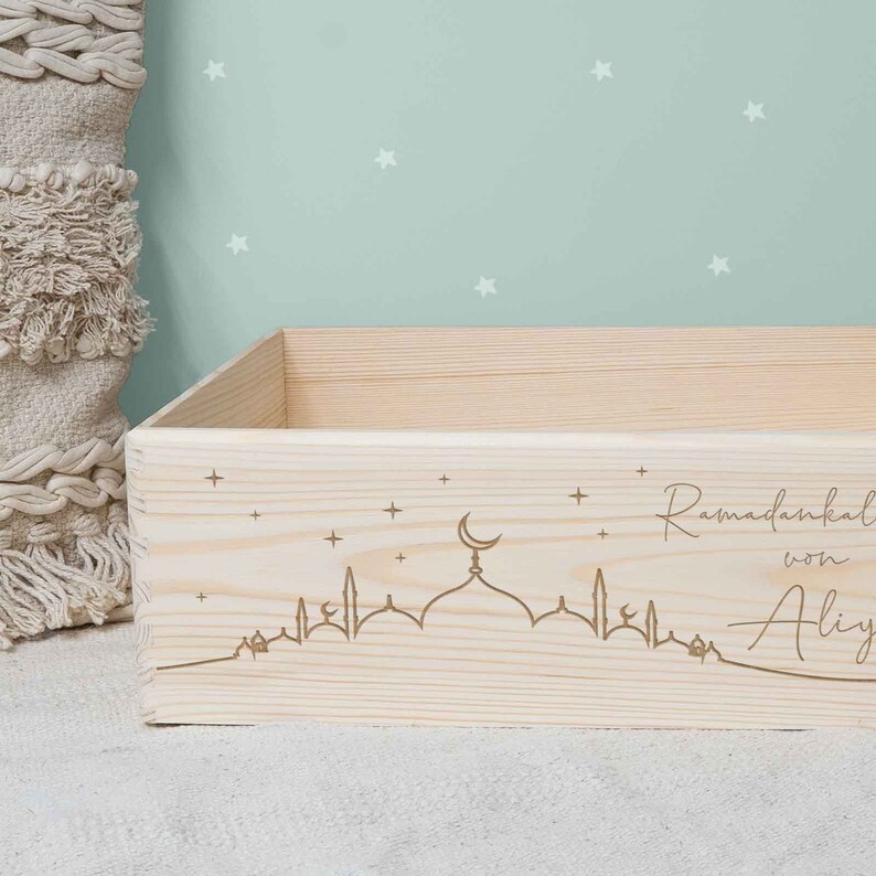May include: A wooden box with a laser-engraved design of a mosque with a crescent moon and stars. The text "Ramadankal von Aily" is also engraved on the box.