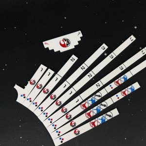 May include: A set of white rectangular game pieces with red and blue symbols. The pieces are numbered 1, 2, and 3. The symbols include a rebel alliance logo, a diamond, and a spaceship.