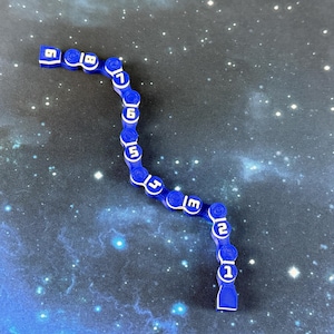 May include: A blue, segmented game piece with white numbers from 1 to 9. The piece is curved and lies on a background that resembles a starry night sky. The numbers are clearly visible.