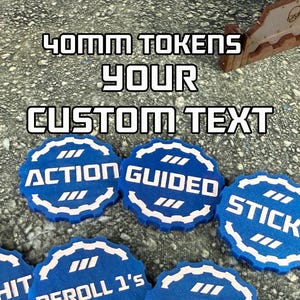May include: Blue and white 40mm tokens with the words "ACTION", "GUIDED", and "STICKY" printed on them. The tokens have a scalloped edge and are arranged on a textured gray surface. The text "YOUR CUSTOM TEXT" is above the tokens.