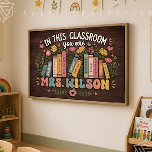 May include: A rectangular wall art print featuring a dark wood grain background with a row of colorful books. The text reads In This Classroom You Are Mrs. Wilson, with individual book spines labeled Kind, Creators, Special, Important, Trusted, Unique, Smart, Respected, Loved, Amazing, Valued, and Good.