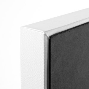 May include: Close-up of the edge of a white canvas print with a black backing.