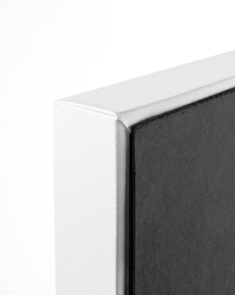 May include: Close-up of the edge of a white canvas print with a black backing.