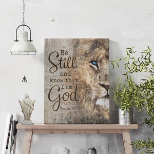 Puede incluir: Una impresi&oacute;n en lienzo con la cara de un le&oacute;n y las palabras "Be Still and know that I am God" con la referencia b&iacute;blica "Salmo 46:10" debajo.