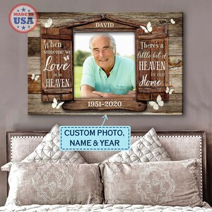 May include: A wooden memorial canvas with a photo of a man in a light blue shirt. The canvas has a window design with the text "When someone we love is in HEAVEN" on the left and "There's a little bit of HEAVEN in our Home" on the right. The text "DAVID 1951-2020" is below the photo.