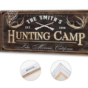 May include: A rustic wooden sign for "The Smith's Hunting Camp" with crossed rifles, antlers, and the text "Lake Morena, California." The sign is brown with white and tan lettering, and the year "1990" is included.