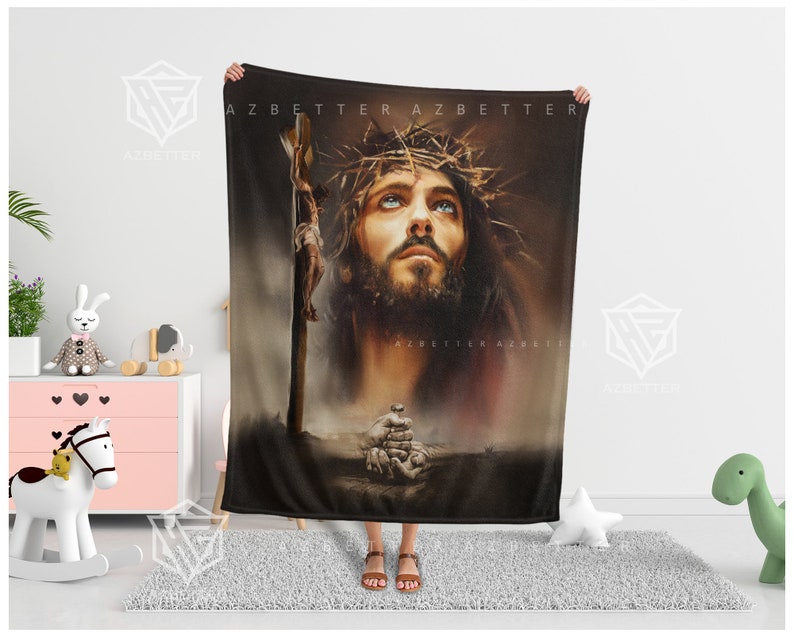 May include: A black fleece blanket with a painting of Jesus Christ on the cross. The painting is in a realistic style and features a close-up of Jesus' face. The background is a dark brown color.