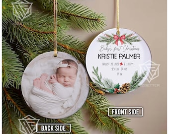 May include: A round Christmas ornament with a gold string, featuring a baby's photo on one side and text on the other. The text reads "Baby's first Christmas" and includes the baby's name, birthdate, time, weight (9.5 lbs, 4 oz), and length (17 in).