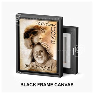 May include: A black framed canvas print featuring a sepia toned image of two men. The man in the foreground is looking up at the man in the background who is gently touching his head. The text "Welcome Home" is printed in a brown font on the canvas. The text "Robert David Cole 12/06/1965 - 10/12/2023" is printed in a black font on the canvas.