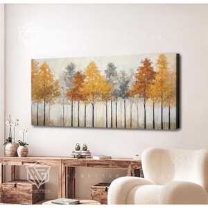 May include: A rectangular canvas artwork showing a line of trees with vibrant foliage. The trees feature gold, orange, and grey hues against a soft backdrop. The painting is displayed above a wooden console table.
