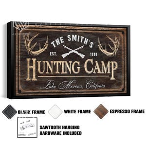 May include: A framed wooden sign with the text "THE SMITH'S HUNTING CAMP" and the location "Lake Morena, California." The sign features crossed rifles, deer antlers, and the year "1990." Available in black, white, and espresso frames. Sawtooth hanging hardware included.