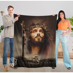 May include: A brown and black fleece blanket with a painting of Jesus Christ wearing a crown of thorns. The painting is in a realistic style and the background is a dark brown color.