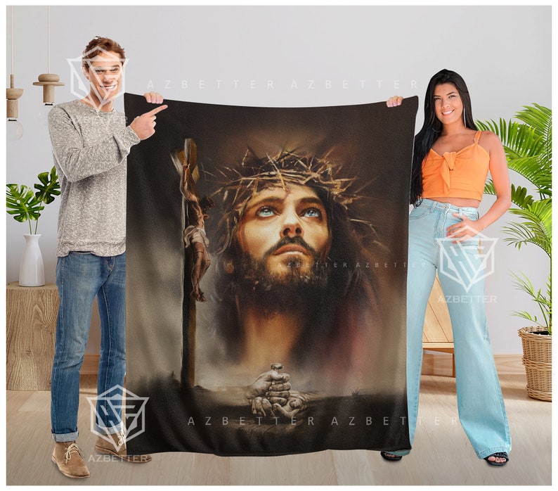 May include: A brown and black fleece blanket with a painting of Jesus Christ wearing a crown of thorns. The painting is in a realistic style and the background is a dark brown color.