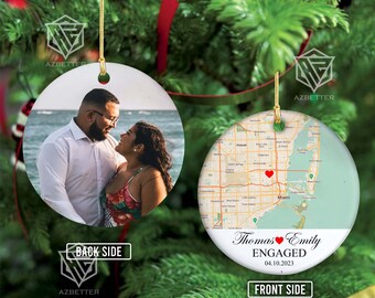 May include: Round ceramic Christmas ornament with a photo of a couple on one side and a map of Miami with a heart on the other. The ornament has gold string for hanging and the text "Thomas & Emily ENGAGED 04.10.2023".