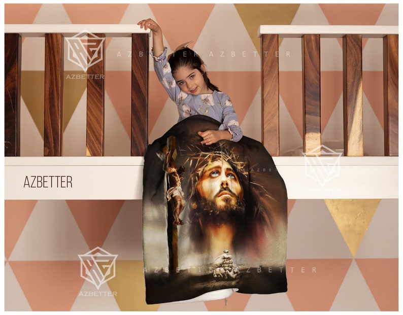 May include: A black and brown throw blanket with a graphic image of Jesus Christ on the cross. The blanket is draped over a wooden railing with a young girl sitting on it.
