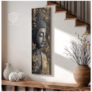 May include: A vertical canvas print featuring a serene Buddha image. The artwork showcases a dark gray Buddha with gold accents, set against a backdrop of gold floral patterns. The print is displayed on a white wall near a wooden shelf.