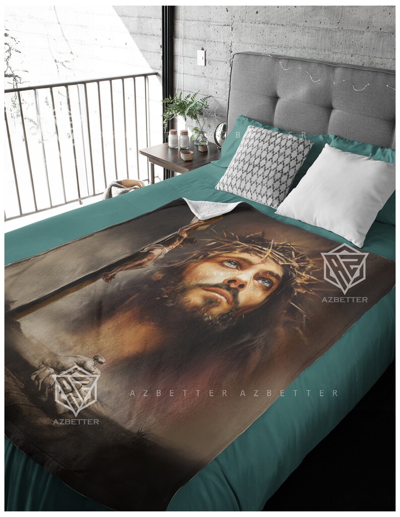 May include: A fleece blanket with a painting of Jesus Christ wearing a crown of thorns. The painting is in shades of brown, gray, and blue. The blanket has the text "AZBETTER" printed on it.