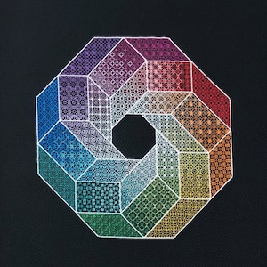 Könnte beinhalten: Ein geometrisches Design mit einer achteckigen Form und einem zentralen Loch. Das Design besteht aus verschiedenen gemusterten Abschnitten in Regenbogenfarben, die vor einem schwarzen Hintergrund weiß umrandet sind. Die Muster umfassen Sterne, Punkte und andere Formen.