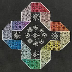 Puede incluir: Un diseño geométrico en forma de cruz sobre un fondo negro. La cruz está compuesta por secciones de colores: rojo, naranja, amarillo, verde, azul, morado y blanco. Cada sección presenta patrones intrincados y motivos florales.