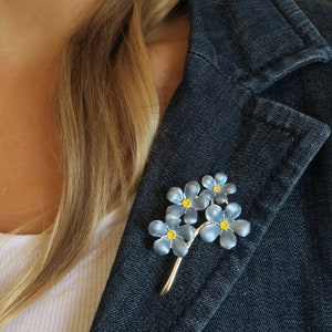 Forget me not blue flower brooch jewellery gift by ATLondonJewels, on a blue denim jacket lapel.