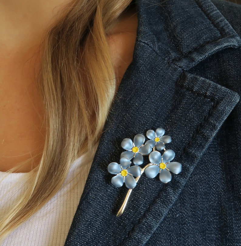 Forget me not blue flower brooch jewellery gift by ATLondonJewels, on a blue denim jacket lapel.