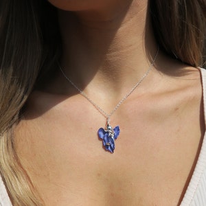 Iris blue flower pendant necklace jewellery gift by ATLondonJewels against a girls neck .