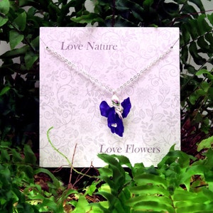 Iris blue flower pendant necklace jewellery gift by ATLondonJewels on a gift card against a foliage background.