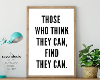May include: A framed print with the text "THOSE WHO THINK THEY CAN, FIND THEY CAN" in bold black letters. The print is in a light brown frame and sits on a wooden shelf with a teal desk lamp and a potted plant.