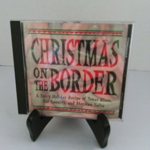 May include: A CD case with a red, white, and green design. The title of the CD is "Christmas on the Border: A Spicy Holiday Recipe of Texas Blues, Hot Country, and Mexican Salsa."