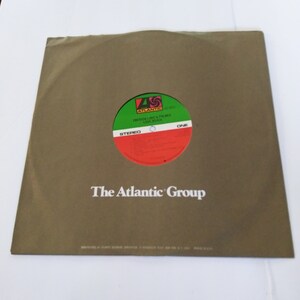 May include: A brown paper record sleeve with the text "The Atlantic Group" printed in white. The sleeve has a green, red, and white record label with the text "Emerson, Lake & Palmer Love Beach" and "Atlantic" printed on it.