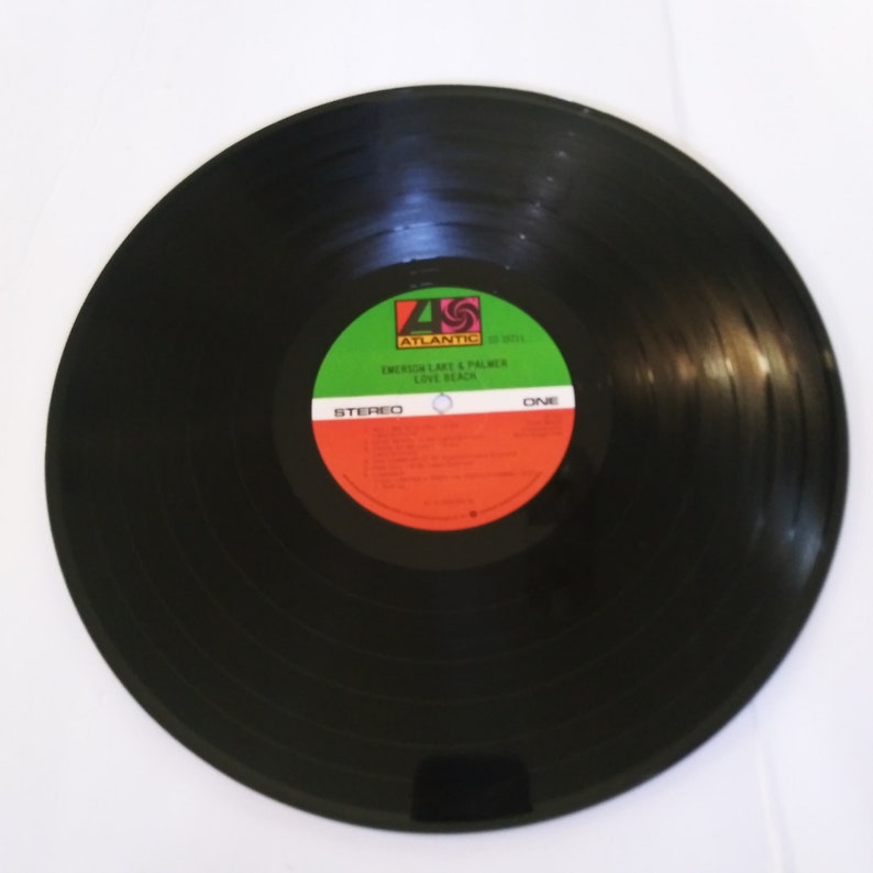 May include: Black vinyl record with a green, red, and white label. The label says "Atlantic" and "Emerson, Lake & Palmer Love Beach".