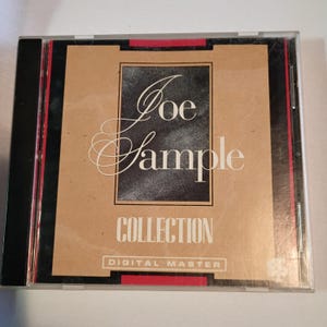 May include: A CD case featuring the album "Collection" by Joe Sample. The cover has a tan background with a black square containing the artist's name in white script. The word "COLLECTION" is in bold white letters, with "DIGITAL MASTER" below.