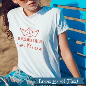 Könnte beinhalten: Weißes T-Shirt mit roter Papierboot-Grafik und dem deutschen Text "IN GEDANKEN BARFUB am Meer...". Das Shirt besteht aus einem weichen Material und eignet sich für Freizeitkleidung. Es hat einen Rundhalsausschnitt.