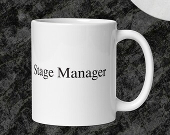 May include: White ceramic coffee mug with black text that reads "Stage Manager".