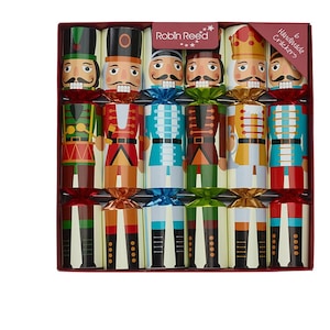 May include: A box set of six handmade Christmas crackers, each designed with a nutcracker soldier theme. The crackers are in various colors, including red, green, blue, and gold, with the "Robin Reed" brand name visible.