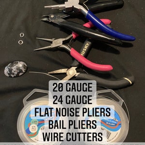 May include: A set of jewelry making supplies including two spools of wire, two pairs of pliers, a pair of wire cutters, two jump rings, and an oval cabochon. The spools of wire are labeled 20 gauge and 24 gauge. The pliers are labeled "Flat Nose Pliers" and "Bail Pliers".