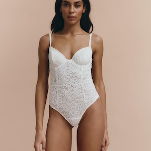 May include: A white lace bodysuit with a scoop neck and adjustable straps.